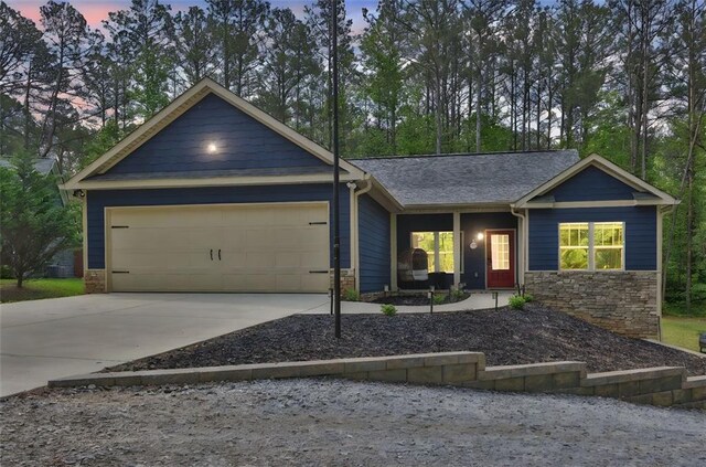 view of front facade with a garage, driveway, and stone siding