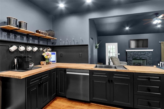 kitchen with stainless steel dishwasher, open shelves, wooden counters, dark cabinetry, and light wood-style flooring