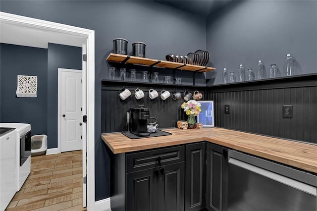 bar featuring separate washer and dryer, baseboards, light wood-style flooring, and wet bar