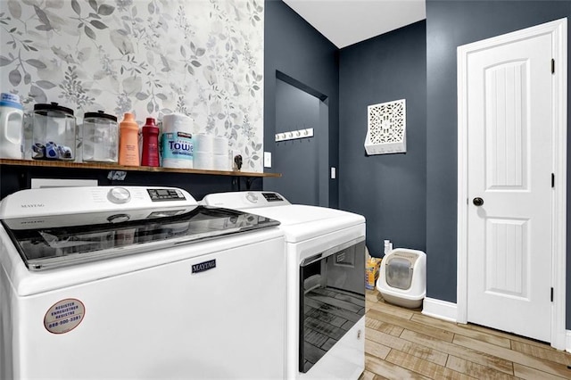 washroom with independent washer and dryer, laundry area, baseboards, and wood finished floors