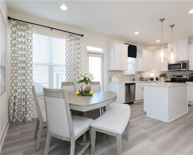 kitchen featuring a kitchen island, white cabinets, decorative backsplash, hanging light fixtures, and stainless steel appliances