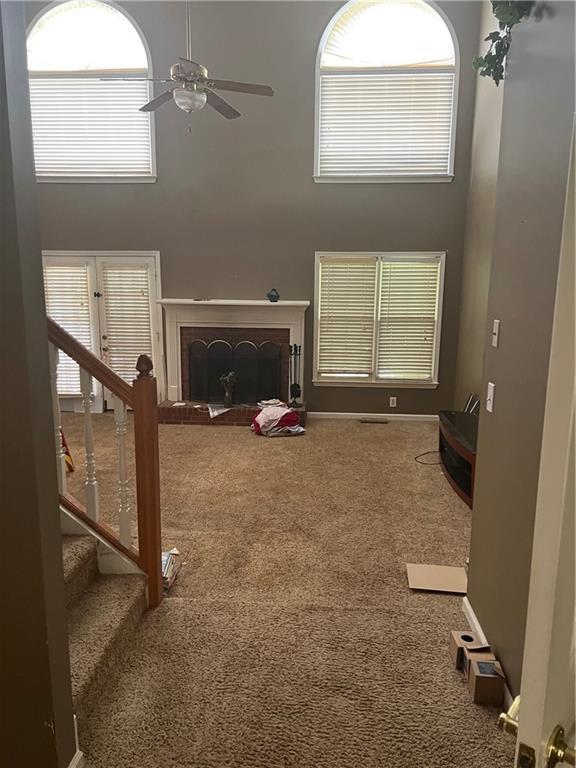 50 Ranger Rd SE, Cartersville, GA 30121 - living room featuring carpet, a high ceiling, ceiling fan, a fireplace with raised hearth, and stairway