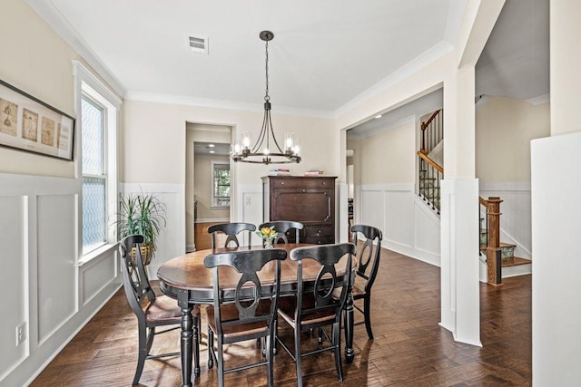 dining room featuring visible vents, dark wood-style floors, an inviting chandelier, a decorative wall, and stairs