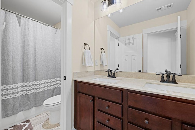 full bathroom featuring a sink, visible vents, toilet, and double vanity