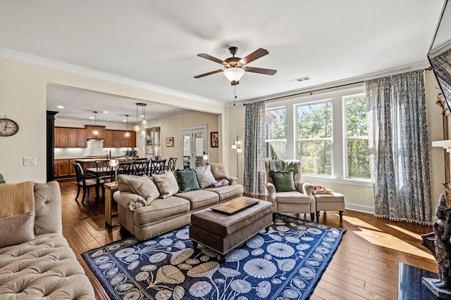 living room featuring visible vents, ornamental molding, a ceiling fan, wood finished floors, and baseboards