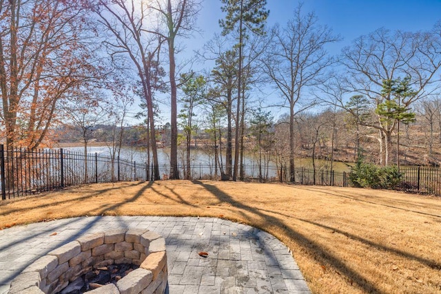 view of yard with a patio, a fire pit, a fenced backyard, and a water view