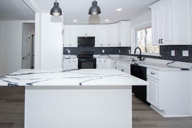 kitchen featuring hanging light fixtures, light wood-style flooring, white cabinetry, a sink, and black appliances