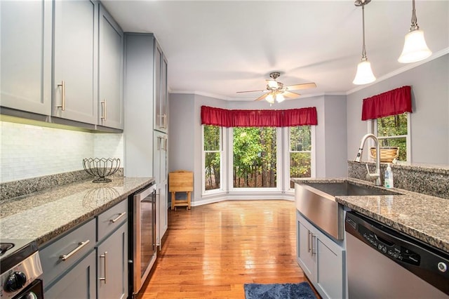 kitchen with gray cabinets, light wood-type flooring, stainless steel dishwasher, and a sink