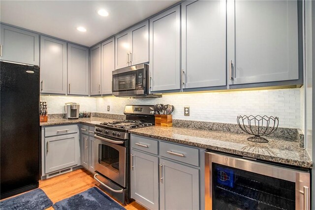 kitchen featuring stone counters, gray cabinetry, beverage cooler, and stainless steel appliances