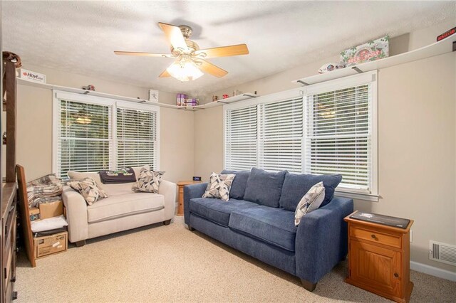 carpeted living room with visible vents, a wealth of natural light, and a ceiling fan