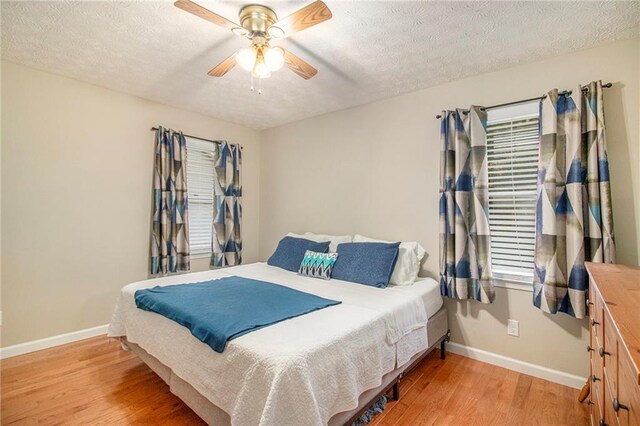 bedroom with baseboards, light wood-style floors, and a textured ceiling