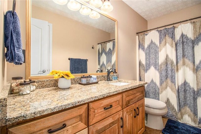 full bath featuring tile patterned floors, toilet, vanity, and a textured ceiling