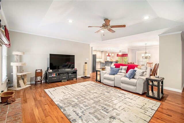 living room with recessed lighting, light wood finished floors, ceiling fan with notable chandelier, and ornamental molding