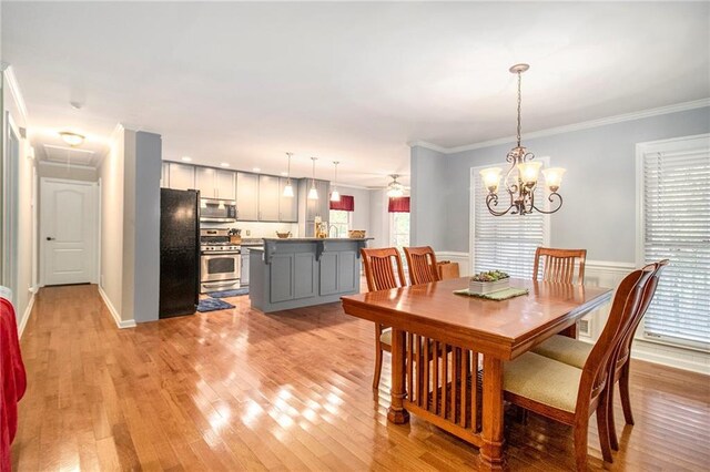 dining room featuring a wealth of natural light, wainscoting, light wood-type flooring, and crown molding
