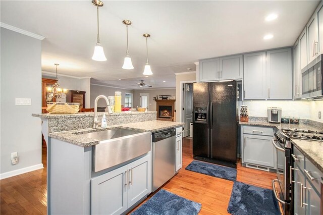 kitchen featuring stainless steel appliances, gray cabinetry, a sink, and ornamental molding