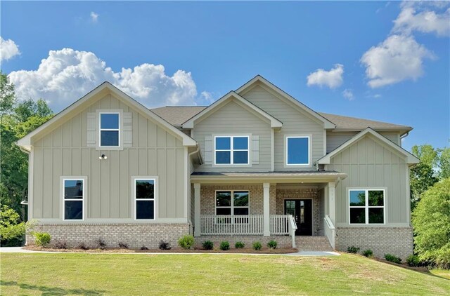 171 Blue Rider Trl, Hoschton, GA 30548 - craftsman-style house with brick siding, a front lawn, board and batten siding, and covered porch
