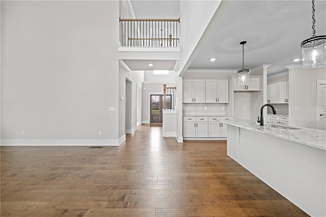 171 Blue Rider Trl, Hoschton, GA 30548 - kitchen featuring light stone countertops, hanging light fixtures, a sink, white cabinetry, and wood finished floors