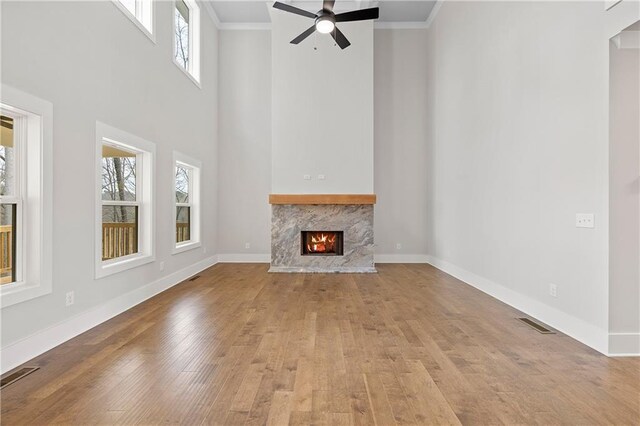 171 Blue Rider Trl, Hoschton, GA 30548 - unfurnished living room featuring wood-type flooring, ornamental molding, a towering ceiling, and visible vents