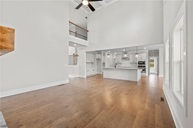 171 Blue Rider Trl, Hoschton, GA 30548 - unfurnished living room featuring a high ceiling, ceiling fan, light wood finished floors, baseboards, and visible vents