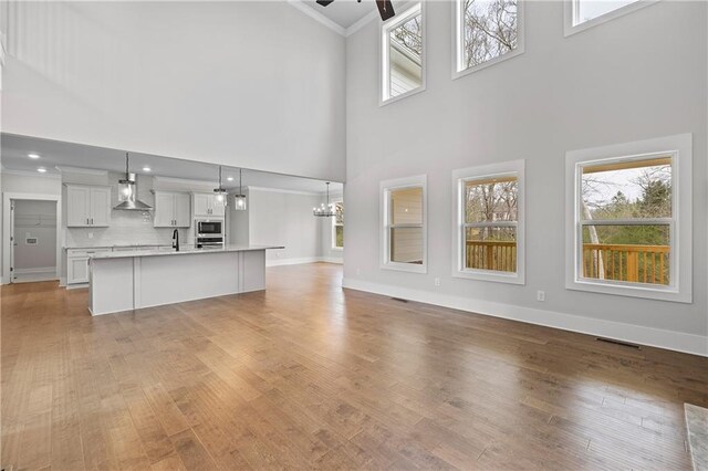 171 Blue Rider Trl, Hoschton, GA 30548 - unfurnished living room with plenty of natural light, visible vents, ornamental molding, and a towering ceiling