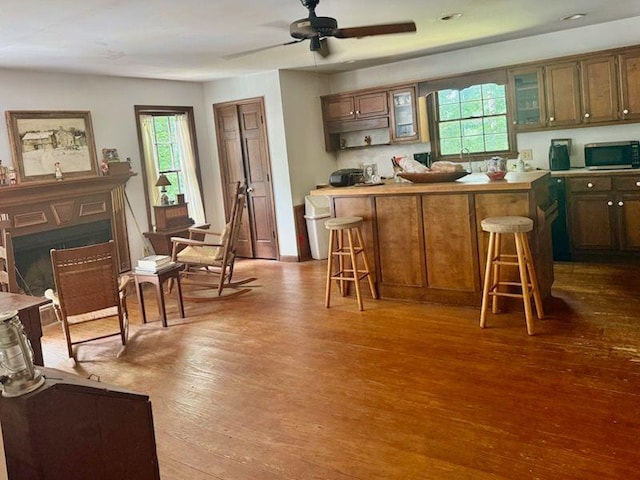 408 Hasty Trl, Canton, GA 30115 - kitchen featuring stainless steel microwave, a kitchen breakfast bar, wood finished floors, glass insert cabinets, and a ceiling fan