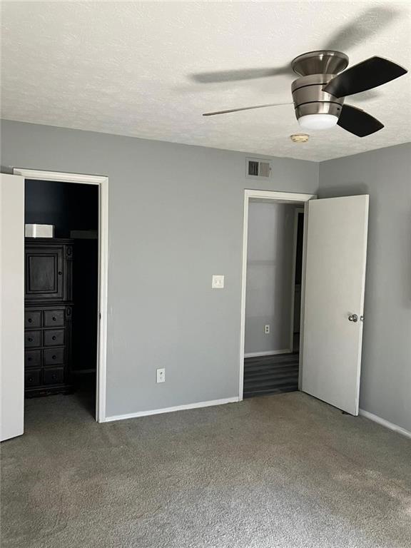 unfurnished bedroom with a closet, ceiling fan, carpet floors, and a textured ceiling