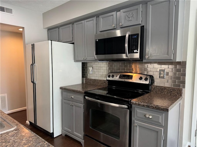 kitchen featuring gray cabinetry, dark hardwood / wood-style flooring, stainless steel appliances, and tasteful backsplash