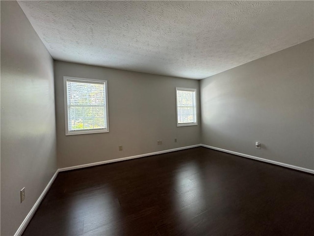 unfurnished room with dark hardwood / wood-style floors and a textured ceiling