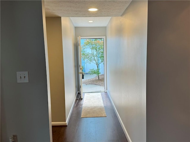 hall featuring a textured ceiling and dark hardwood / wood-style floors