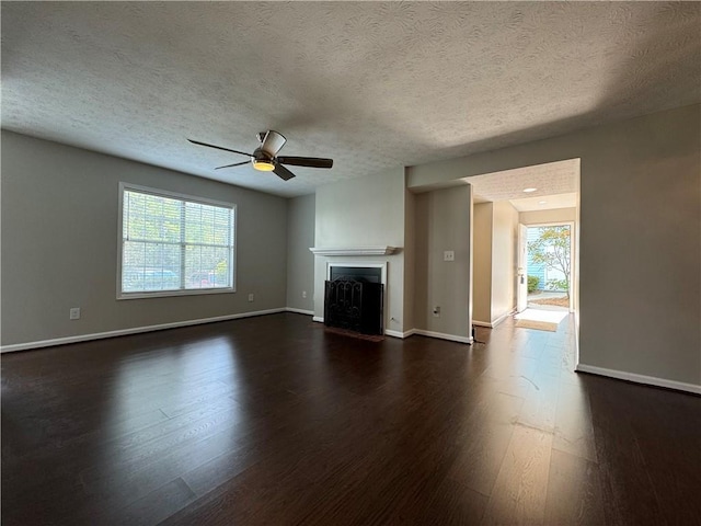 unfurnished living room featuring a textured ceiling, dark hardwood / wood-style floors, ceiling fan, and a healthy amount of sunlight