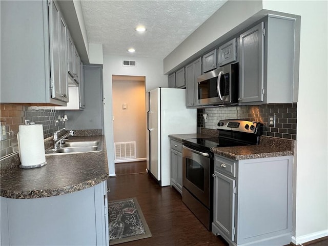 kitchen with gray cabinetry, sink, dark hardwood / wood-style floors, a textured ceiling, and appliances with stainless steel finishes