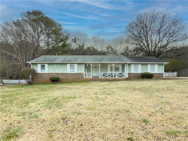 ranch-style house featuring covered porch, brick siding, fence, and a front lawn