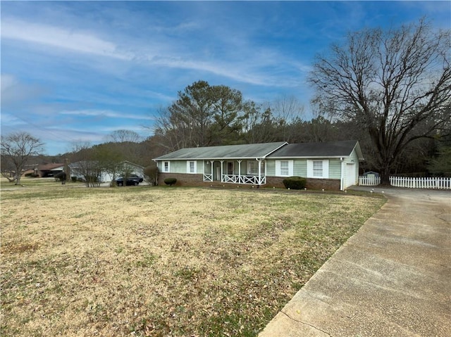 ranch-style house featuring driveway, an attached garage, fence, a front yard, and brick siding