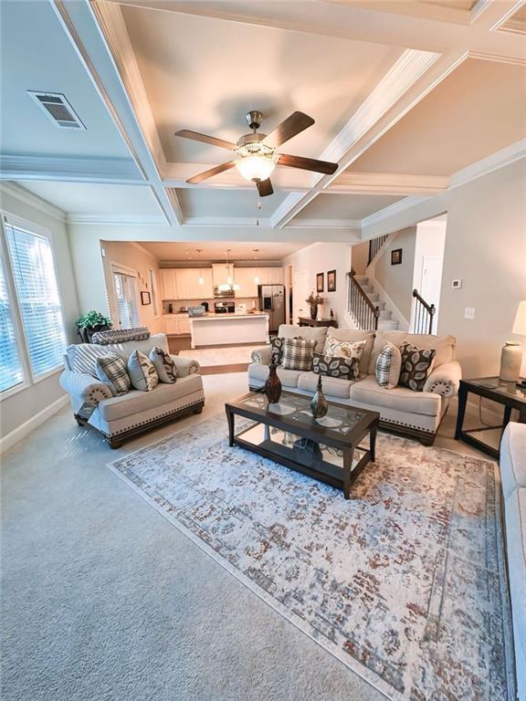 living room with visible vents, coffered ceiling, ceiling fan, and stairway