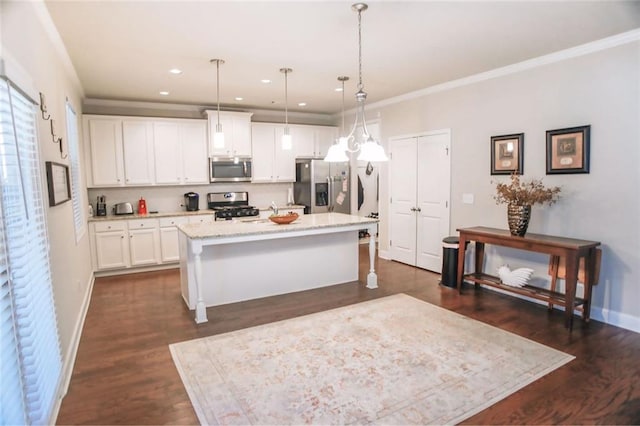 kitchen featuring baseboards, an island with sink, stainless steel appliances, crown molding, and white cabinetry