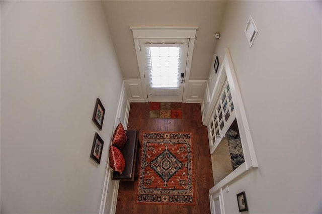 entrance foyer featuring a decorative wall, wood finished floors, and wainscoting