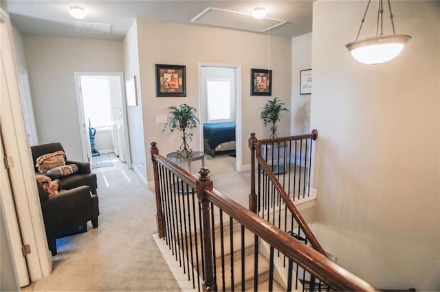 corridor featuring light carpet, attic access, baseboards, and an upstairs landing