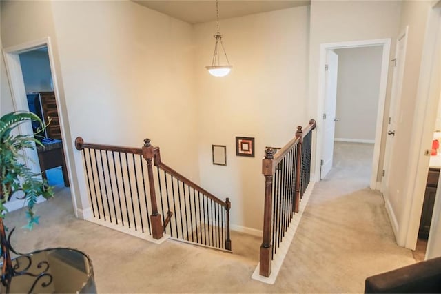 hall featuring baseboards, carpet flooring, and an upstairs landing