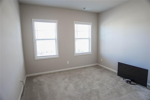 carpeted spare room featuring visible vents and baseboards