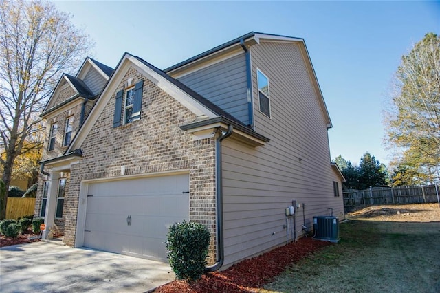 view of property exterior with concrete driveway, an attached garage, fence, central AC, and brick siding