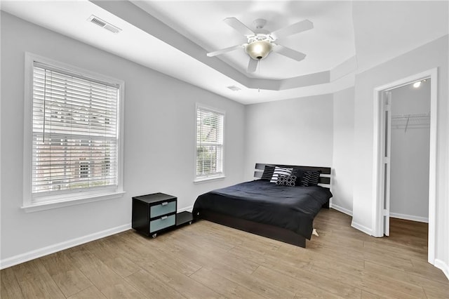 2207 Concordia Way SE Unit 12, Mableton, GA 30126 - bedroom featuring light wood-style flooring, baseboards, a walk in closet, a tray ceiling, and a ceiling fan