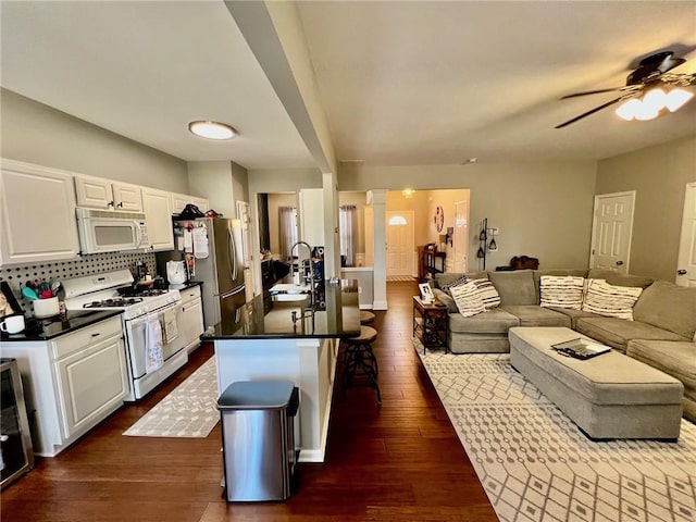 kitchen featuring dark wood-type flooring, a sink, dark countertops, open floor plan, and white appliances