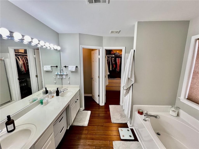 full bath featuring a bath, double vanity, hardwood / wood-style flooring, and a sink