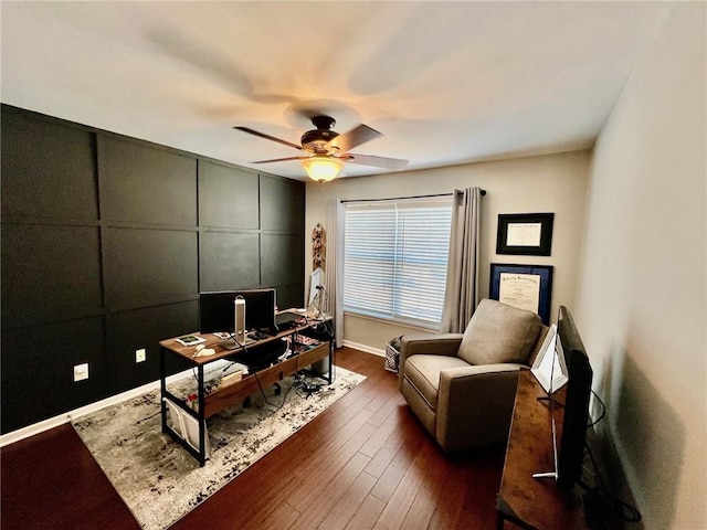 office area with dark wood finished floors, a ceiling fan, and a decorative wall