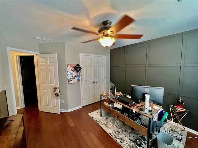 office with baseboards, wood finished floors, a ceiling fan, and a decorative wall