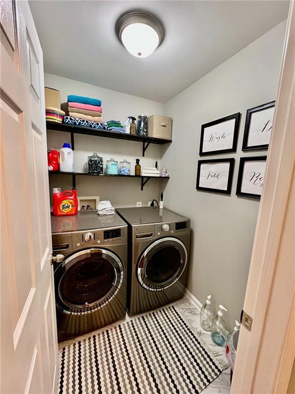 washroom featuring washer and clothes dryer, laundry area, marble finish floor, and baseboards