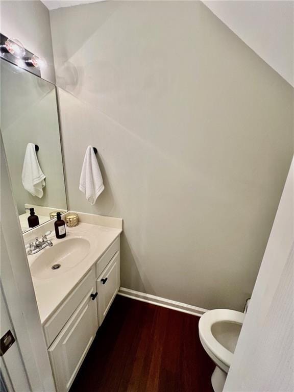 bathroom featuring vanity, toilet, wood finished floors, and baseboards