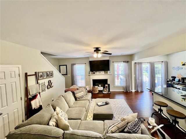 living room featuring a fireplace, dark wood-type flooring, and a ceiling fan