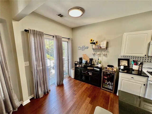 bar featuring visible vents, dark wood-type flooring, backsplash, wine cooler, and white stove