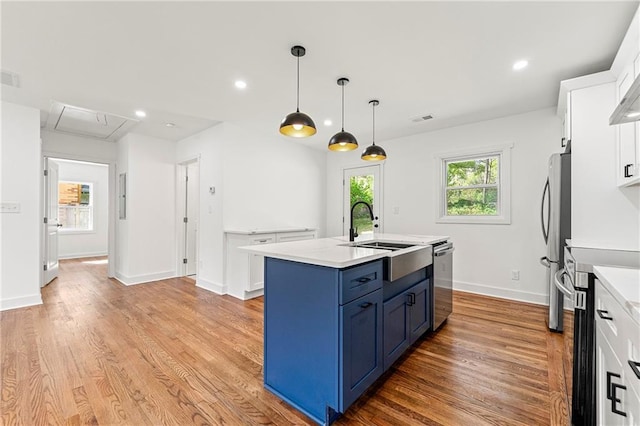 2146 Trailwood Rd, Decatur, GA 30032 - kitchen with a kitchen island with sink, white cabinetry, light countertops, blue cabinetry, and appliances with stainless steel finishes